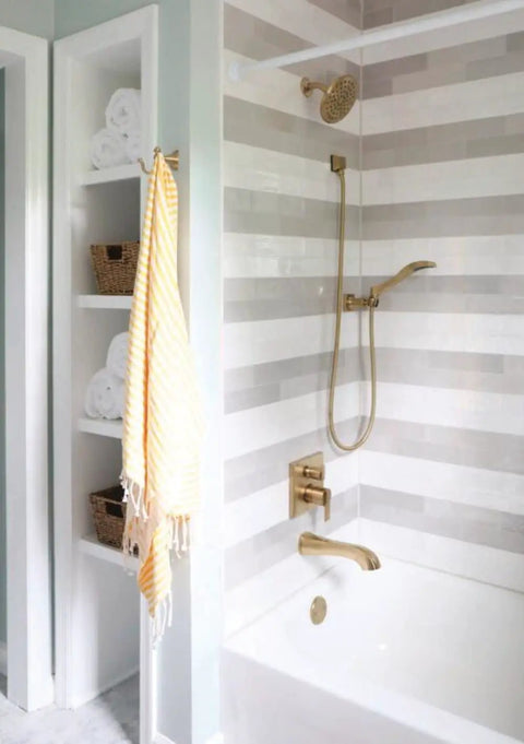 Modern bathroom with striped tile, champagne bronze fixtures, and Universal Showering Wall Elbow In Champagne Bronze With Lumicoat Finish For Hand Showers No Fuss Clean Modern Square Design Resists Mineral Buildup And Hard Water Stains Compatible With Most Hand Showers For New Construction Install.