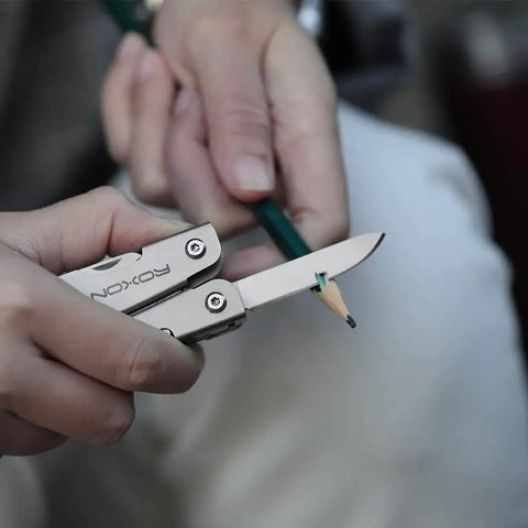 Close-up of 14 In 1 Mini Multitool Lightweight with Folding Scissors carving a pencil, showcasing its compact design and functionality.