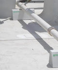 Front view of 4-pack white PVC rooftop pipe support blocks on a flat white roof with Rooftop logo