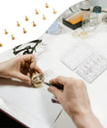 Pro Grade Copper Watch Dial Feet Assortment Kit in use on a workbench with a storage box and small precision tools.