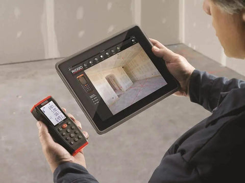 Micro Laser Distance Meter With Bluetooth Sync And Tilt Sensor in use, paired with tablet showing measurement data.