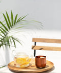 Renewed 6 Oz Smart Heated Coffee Mug With App Precision Temp Control And Solid Battery Life Keeps Your Favorite Brew Piping Hot And Ready For All Day Sipping Sessions on a wooden tray with a glass teapot.