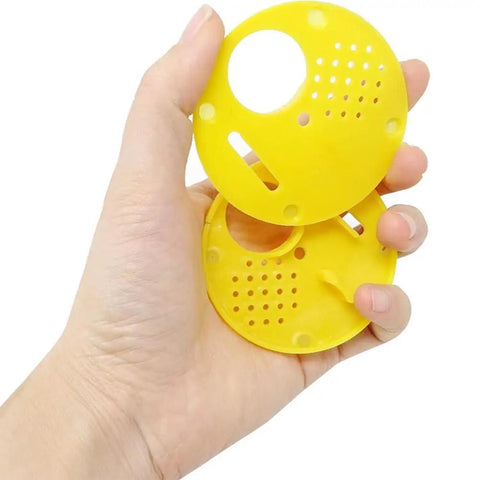 Beekeeping Entrance Gate Set for Nuc Boxes, shown hand holding yellow plastic beehive gates with vent holes