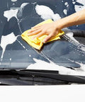 Close-up of yellow Amazon Basics microfiber cleaning cloth in use to wipe a car windshield.