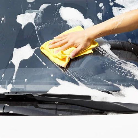 Close-up of yellow Amazon Basics microfiber cleaning cloth in use to wipe a car windshield.