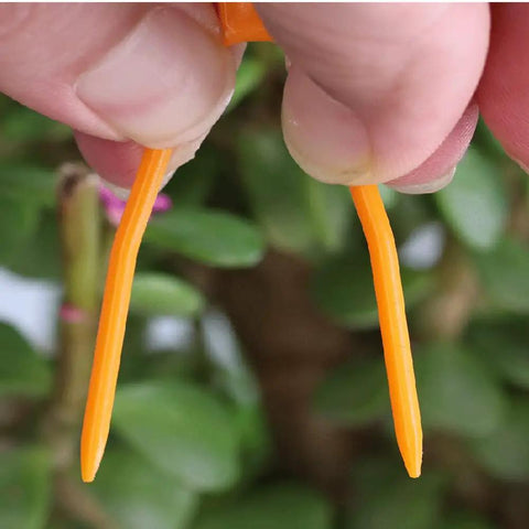 Close-up of orange plastic tips from Set Of 100 Plastic Planting Forks For Strawberries And Grapevines, held between fingers.