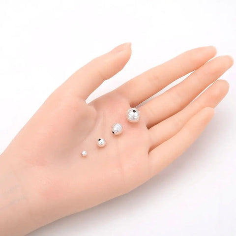 500 Pcs 4mm Sterling Silver Plated Brass Corrugated Round Bead Spacers for DIY Jewelry Making displayed on a hand