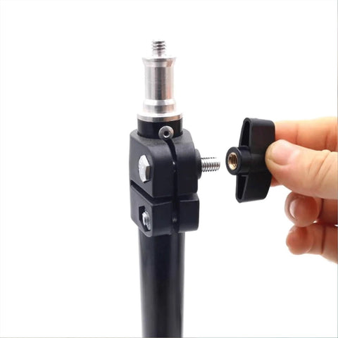 Close-up of black plastic 1/4-inch wing knob with brass insert being threaded into a metal clamp on a woodworking jig
