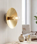 NautiGlow Modern Brass Brushed Wall Sconce with Round Backplate, Exposed Globe Light Fixture for Bedroom, Living Room, Hallway & Entryway mounted on textured wall.
