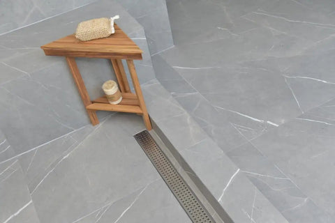 Heavy Duty 47 Inch Linear Shower Drain With Slick Brushed Nickel Finish Solid 304 Stainless Steel Frame Built Tough For Tile Floors Features Quick Drain Hair Catcher Strainer For A No Sweat Bathroom Upgrade by the wooden shelf in a modern tiled bathroom.