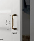 Antique Brass Fluted Cabinet Pulls, 3 Inch Hole Centers, attached to a white cabinet, showing size dimensions