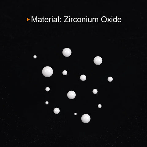 White zirconium oxide ceramic bearing balls in varying sizes scattered on a black background.