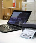 No Sweat Usb Shipping Label Printer Commercial Grade 4x6 Thermal printing a shipping label beside a laptop in a warehouse.