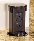 Slick Round Kitchen Pop Up Outlet Box With Two Full Size Receptacles And Dual USB Fast Charge Ports Hardwired Countertop Power Hub with black finish on granite