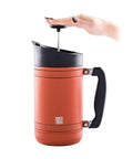 Insulated French Press Keeps Your Daily Joe Hella Hot For Hours With Tough Stainless Steel Build And Secure Twist Lid Crafted For Cabin Weeks And Backyard Chillin 32 Fl Oz Red Rock in use with a hand pressing down.