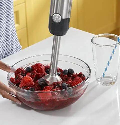 No Sweat 500 Watt Stainless Steel Immersion Blender With Removable Whisk And Spout Blending Jar blending fruit in bowl.