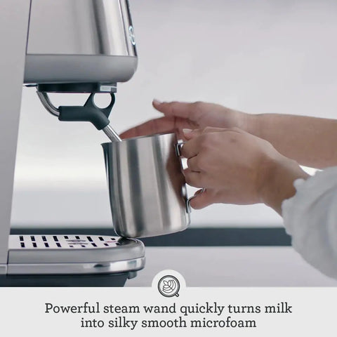 Compact Espresso Machine With 54mm Portafilter And 19 Gram Dose Auto Steam Wand For Milky Microfoam Barista Vibes Third Wave Pro Grade Coffee At Home Brushed Stainless Steel Finish Easy One Touch Espresso And Milk Texturing in use, with steam wand frothing milk in metal jug.