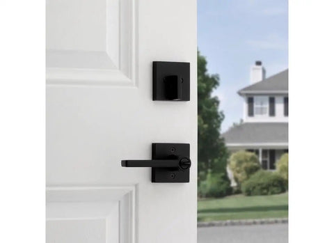 Matte Black Keyed Entry Lever And Deadbolt Combo With SmartKey For Easy Lockup on white door, view from inside with house outside