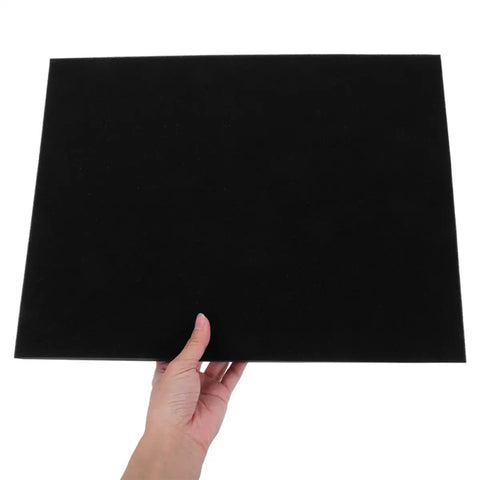 Hand holding black polyurethane packing foam padding sheet for shipping and packaging ceramics and electronics, flexible pro grade.