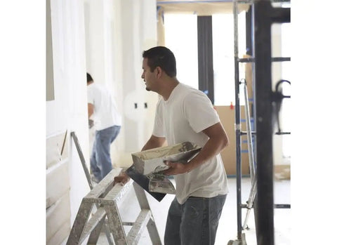 Worker using 18Lb EZ Sand 45 Joint Compound for drywall and painting projects, applying sandable gypsum formula for smooth finish.