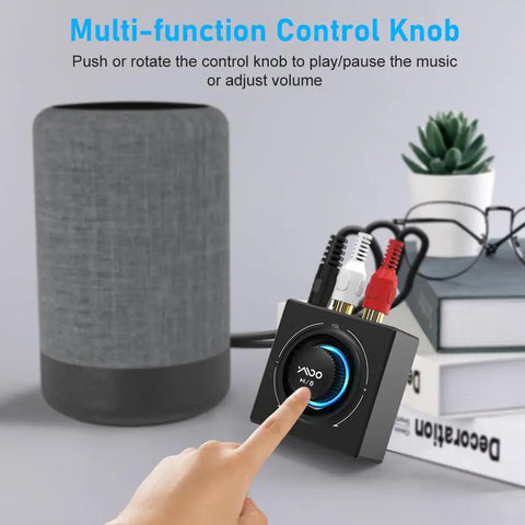 Bluetooth 5.3 Receiver And RCA Audio Adapter with control knob next to a speaker on a desk, showing front view.