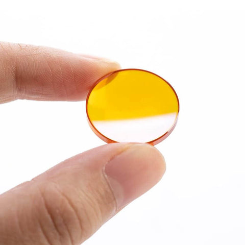 Close-up of 18mm PVD ZnSe CO2 laser focus lens held between fingers.