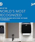 Two black Scott toilet paper dispensers mounted on a tiled restroom wall under a blue Scott banner.