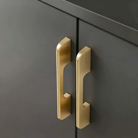 Close-up of Five Pack Solid Brushed Gold Cabinet Handles for kitchen cabinets, dressers and furniture, mounted on gray doors.