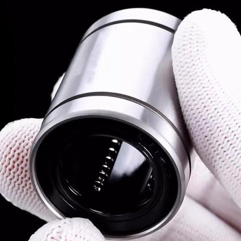 Close-up of a silver cylindrical linear motion bearing (LMB16LUU) held in gloved hands.