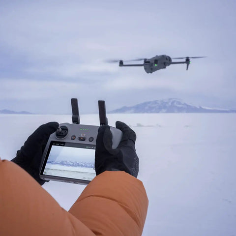 Person operating Mavic 4 Pro Drone With 100MP Hasselblad 4/3 CMOS Main Camera And Dual Tele Lenses, outdoor snow scene