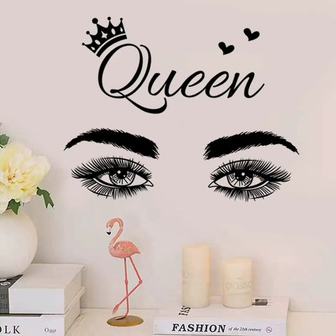 Queen wall decal with crown and eyes above books, candles, and flamingo decor on shelf