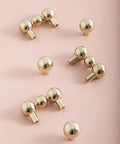 Heavy Duty Solid Brass Cabinet Knob With A Slick Single Hole Design And Top Shelf Modern Hardware Upgrade For Kitchens Cupboards Wardrobes And Bedroom Furniture, close-up of rounded knobs on pink background.