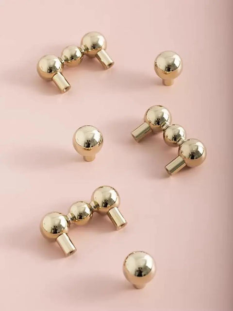 Heavy Duty Solid Brass Cabinet Knob With A Slick Single Hole Design And Top Shelf Modern Hardware Upgrade For Kitchens Cupboards Wardrobes And Bedroom Furniture, close-up of rounded knobs on pink background.