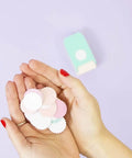 Hands holding multicolored paper circles made with the multimaterial scalloped circle punch for card making scrapbooking and DIY craft projects