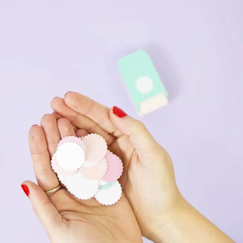 Hands holding multicolored paper circles made with the multimaterial scalloped circle punch for card making scrapbooking and DIY craft projects