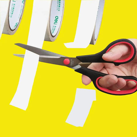 Hand using Go To Ultra Sharp 8.5 Inch Multipurpose Scissors With Comfort Grip to cut paper against a yellow background.