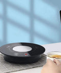 Fast Acting USB Mug Warmer With Smart Adjustable Heat Control Keeps Your Morning Sip Piping Hot All Day Long Sleek Black Tempered Glass Platform on a desk with a cup of tea.
