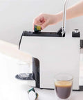 Side view of Durable Smart Capsule Coffee Machine With Drip Free Design No Mess One Tap Operation Two Modes Italian Espresso And American Coffee Compact Electric Brewer For Home Use with capsule being inserted.