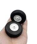 Hand holding two 2 Inch Foam Wheel Set With Plastic Hub For RC Planes And Helicopters Ultra Lightweight Sponge Tire Replacement