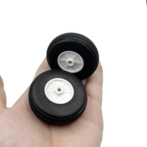 Hand holding two 2 Inch Foam Wheel Set With Plastic Hub For RC Planes And Helicopters Ultra Lightweight Sponge Tire Replacement