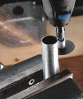 Dremel-style rotary tool cutting a metal tube in a vise; sparks.