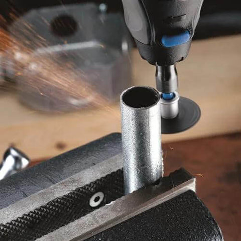 Dremel-style rotary tool cutting a metal tube in a vise; sparks.