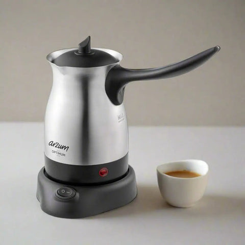 Electric Turkish Coffee Maker With Boil Dry Protection In Stainless Steel 600 Milliliter Capacity sitting next to a cup of coffee