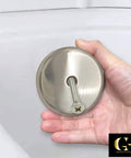 Top Shelf Single Hole Bathtub Overflow Drain Cover Plate With Brushed Nickel Finish held in hand, showcasing its metal build and screw detail.