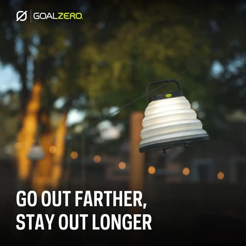 Crush Light Solar Powered Camping Lantern hanging outdoors during evening, with collapsible design and USB rechargeable battery.