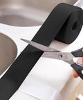 Person cutting Seamless Self Adhesive Shower Sink Caulk Strip Tape Sealing Solution for Bathroom Tub and Tile.