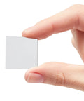 Hand holding a single 1x1 inch mini square mirror tile from 120 Pack Mini Square Mirror Tiles 1x1 Inch For Mosaic Art And Crafts, DIY Home Decor Backsplash.