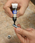 Applying removable gel threadlocker to metal bolt, medium strength, no drip formula, cures in 24 hours, ideal for DIY projects.