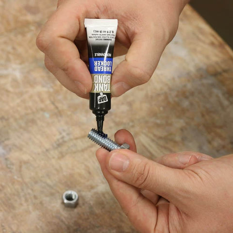 Applying removable gel threadlocker to metal bolt, medium strength, no drip formula, cures in 24 hours, ideal for DIY projects.
