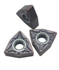 Three WNMG carbide turning inserts, triangular with central mounting hole, bronze-gray finish.